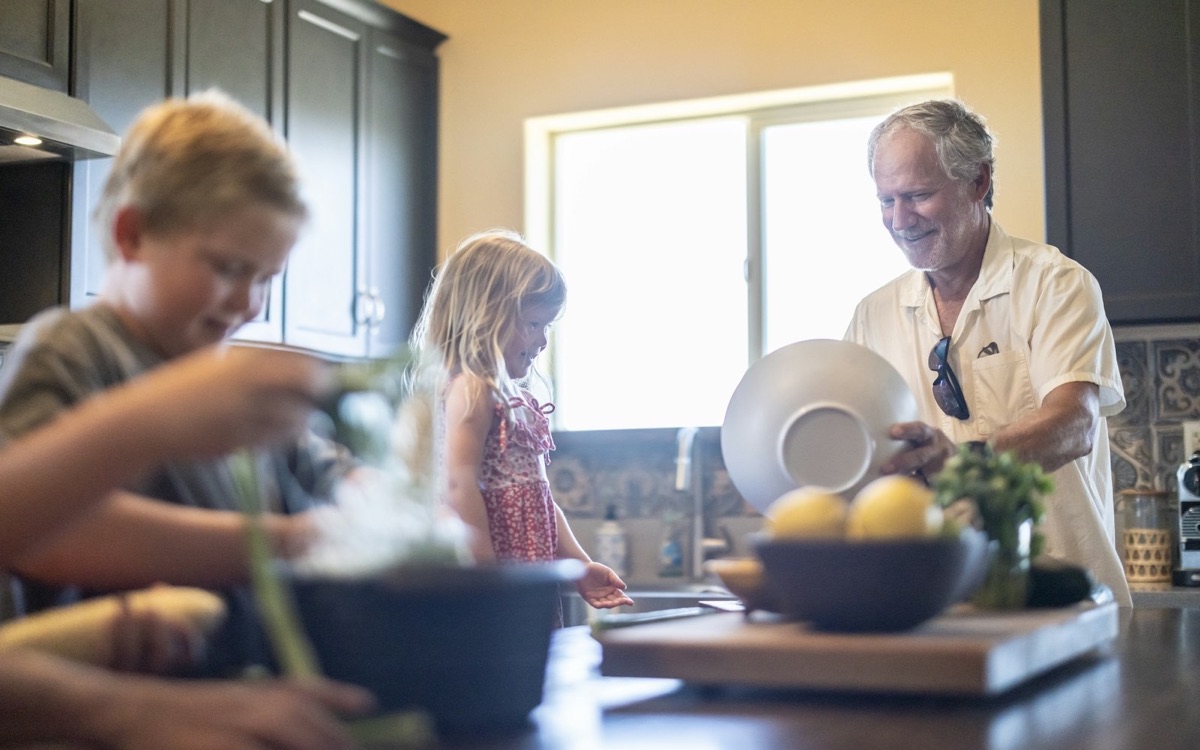 A grandfather and grandchildren learning together in a warm kitchen
