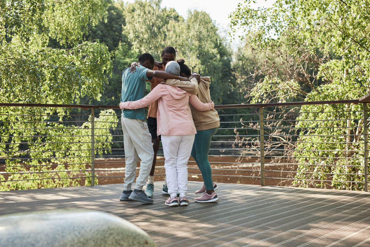 A small group of people embracing outdoors, supporting one another